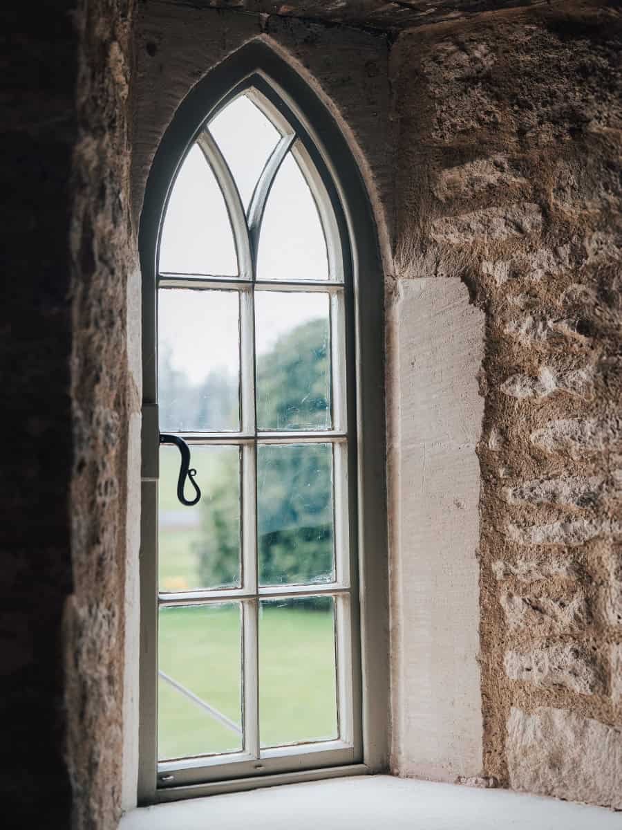 Ivy Lodge restored Gothic pointed-arch window in deep stone reveal, looking out to Cirencester parkland